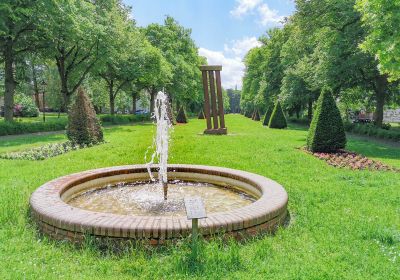 Grünanlage zwischen den Spuren der Adalbertstraße mit Springbrunnen, abstrakter Skulptur und im Hintergrund der Christus- und Garnisonkirche