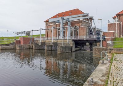 Am Ende eines Gewässers steht ein Klinkergebäude, daneben eine Hubbrücke. Das Gewässer fließt unter dem Gebäude durch.