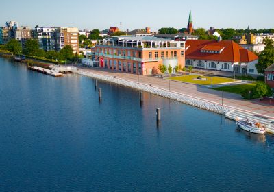 Luftbildaufnahme vom Wasser aus in Richtung Land. Hinter der Treppenanlage im Großen Hafen das Gebäude des TheOs.