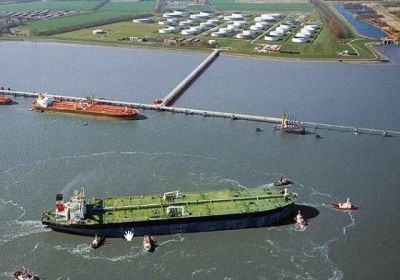 Luftbildaufnahme der Tankerlöschbrücke im Vordergrund. Am oberen Bildrand ist das Festland mit zahlreichen weißen Tanks zu erkennen. 