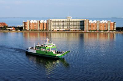 Luftbild über den Großer Hafen. Die Nordsee im Hintergrund wird durch einen schmalen bebauten Streifen getrennt, auf dem das Helgolandhaus steht.