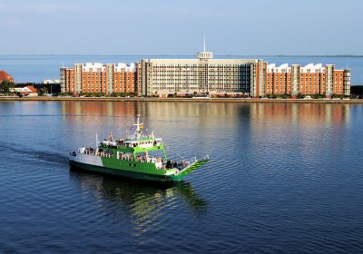 Luftbild über den Großer Hafen. Die Nordsee im Hintergrund wird durch einen schmalen bebauten Streifen getrennt, auf dem das Helgolandhaus steht.