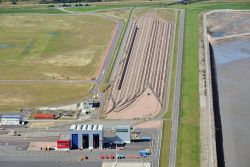 Luftaufnahme des Vorstellbahnhofs des Containerterminals. Im Vordergrund ist eine Halle zu erkennen, in deren geöffneten Toren einer der Van-Carrier zu erkennen ist.